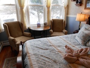 A hotel room with a bed, two armchairs, a small round table, and a lamp.