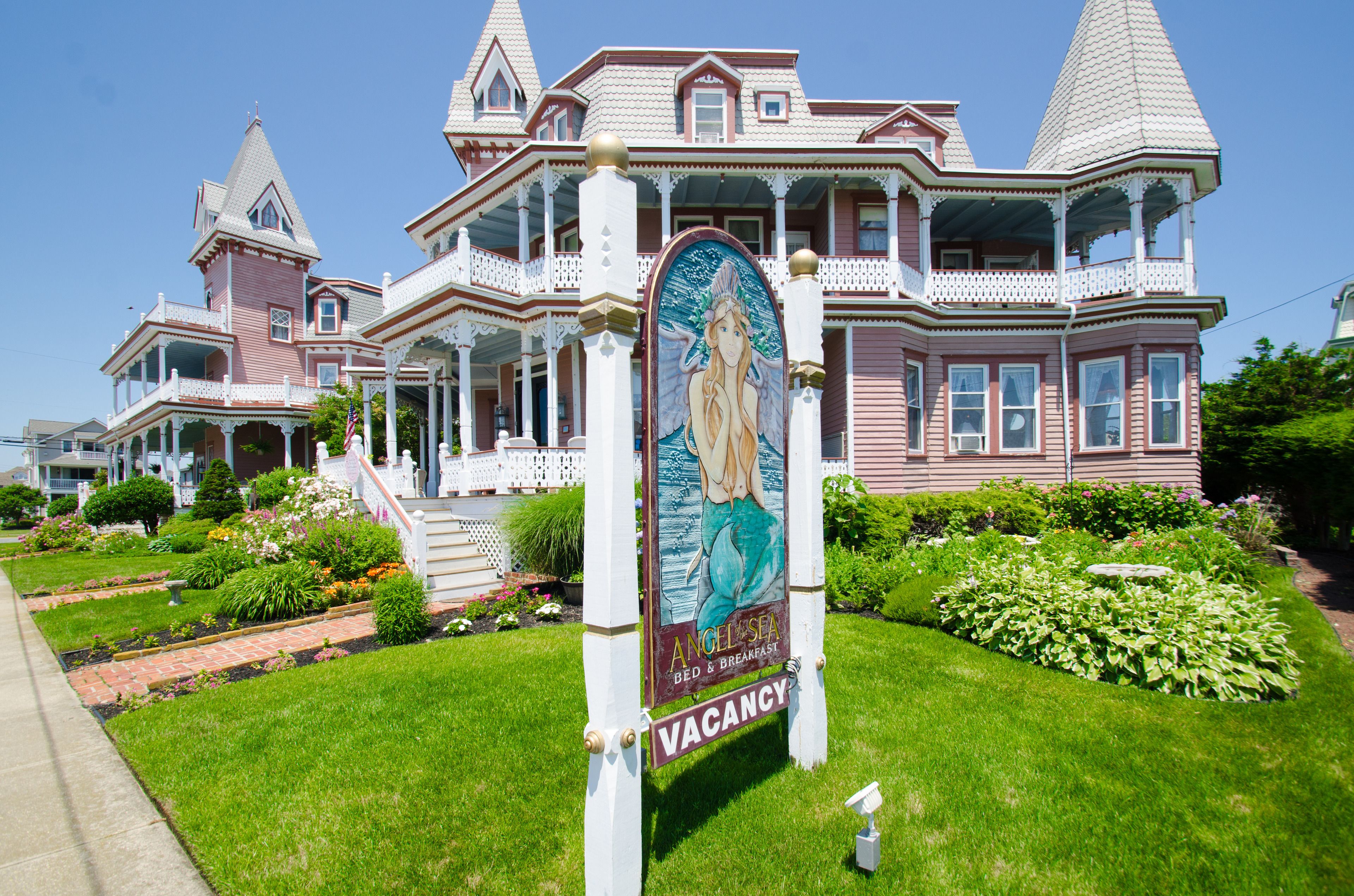 A Victorian-style house with a large porch, a sign advertising a bed and breakfast, and a well-maintained garden.