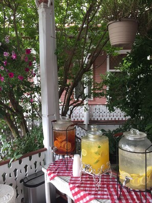 An outdoor patio with a table set for drinks, surrounded by greenery and a white fence.