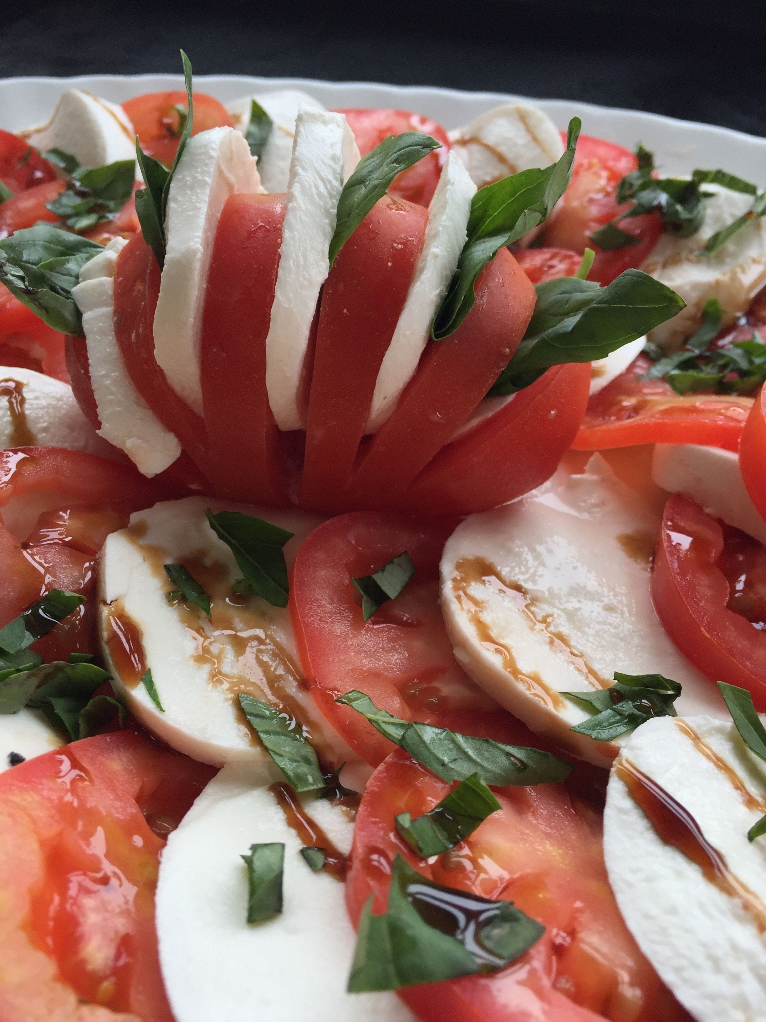 A close-up of a tomato and mozzarella salad with basil leaves.