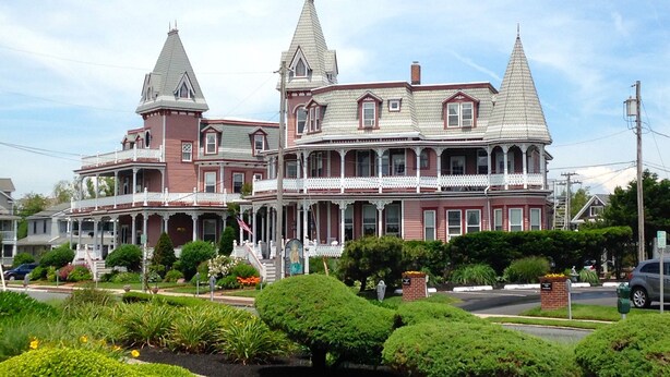 A large, historic house with a prominent tower and a wrap-around porch.