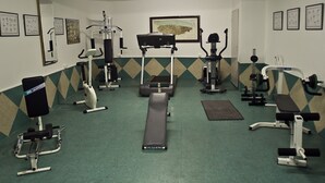 A gym with various exercise equipment, a bench, and a wall-mounted picture. - Doña Nieves (Norena)