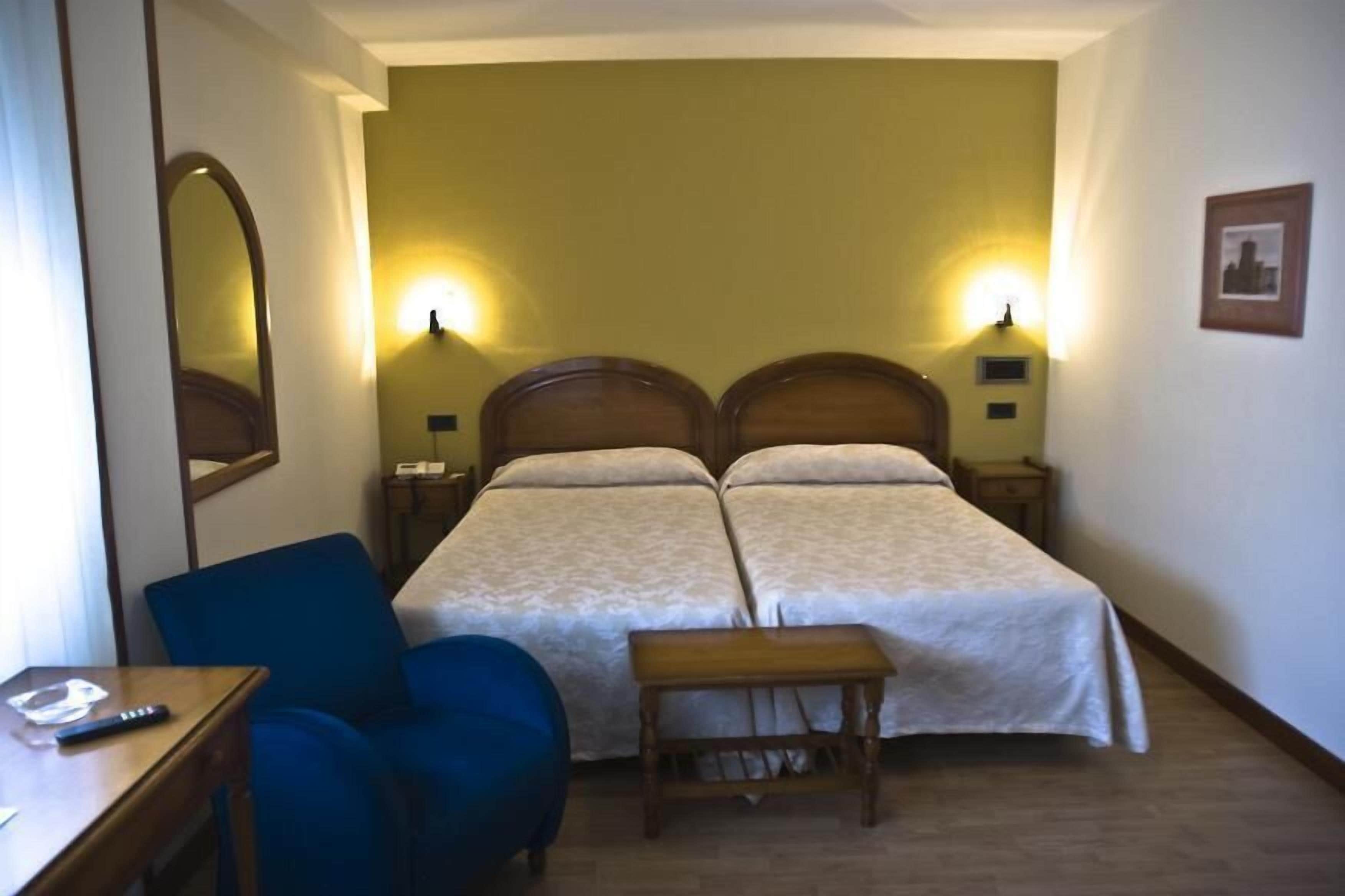 Een hotelkamer met twee bedden, een bureau, een stoel en een klein tafeltje.