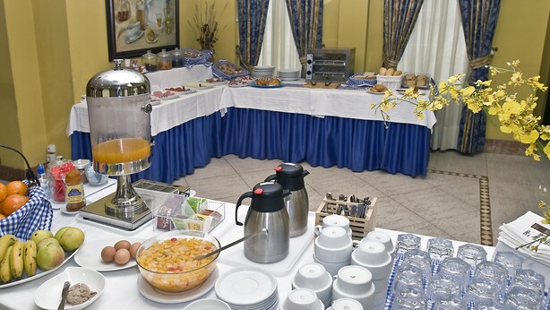 A buffet setup with various food items, a beverage dispenser, and a coffee maker. - Doña Nieves (Norena)