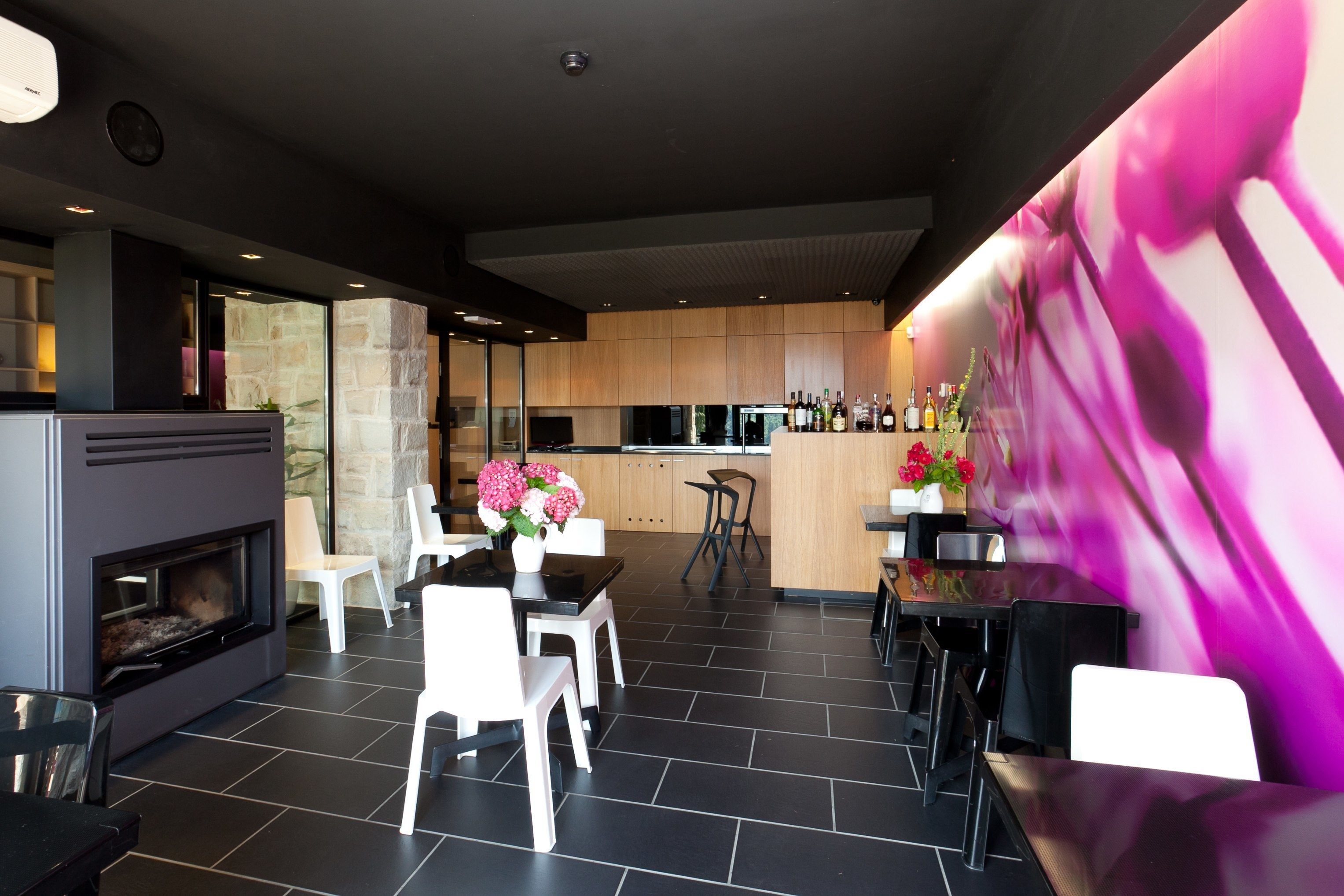 Una cocina moderna con una pared de acento de piedra, chimenea y comedor con sillas blancas.