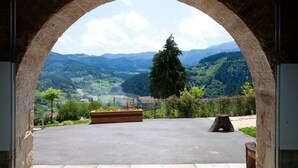 A stone archway framing a view of a mountainous landscape with a wooden planter and a tree stump in the foreground. - Ellauri Hotel, Landscape SPA - Adults Only (Zeanuri)
