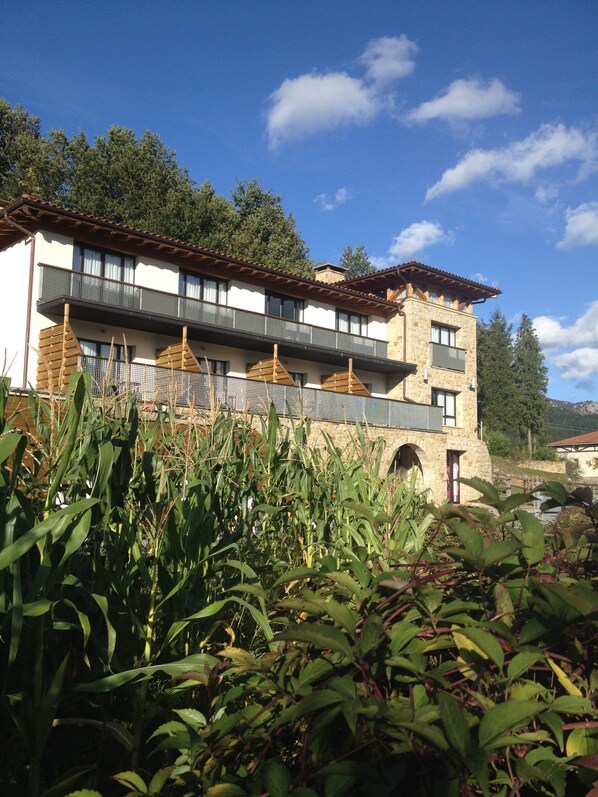 A multi-story building with balconies, surrounded by greenery and trees. - Ellauri Hotel, Landscape SPA - Adults Only (Zeanuri)