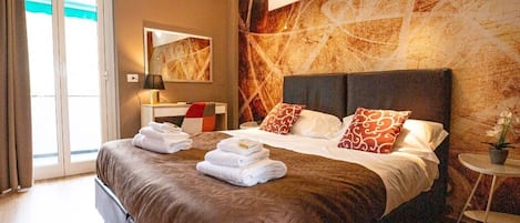 Una habitación de hotel moderna con una cama grande, una mesita y vistas al exterior.