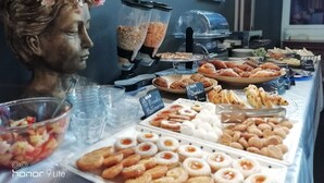 A buffet with various pastries and a statue of a woman. - Hotel Sereno (Sestri Levante)