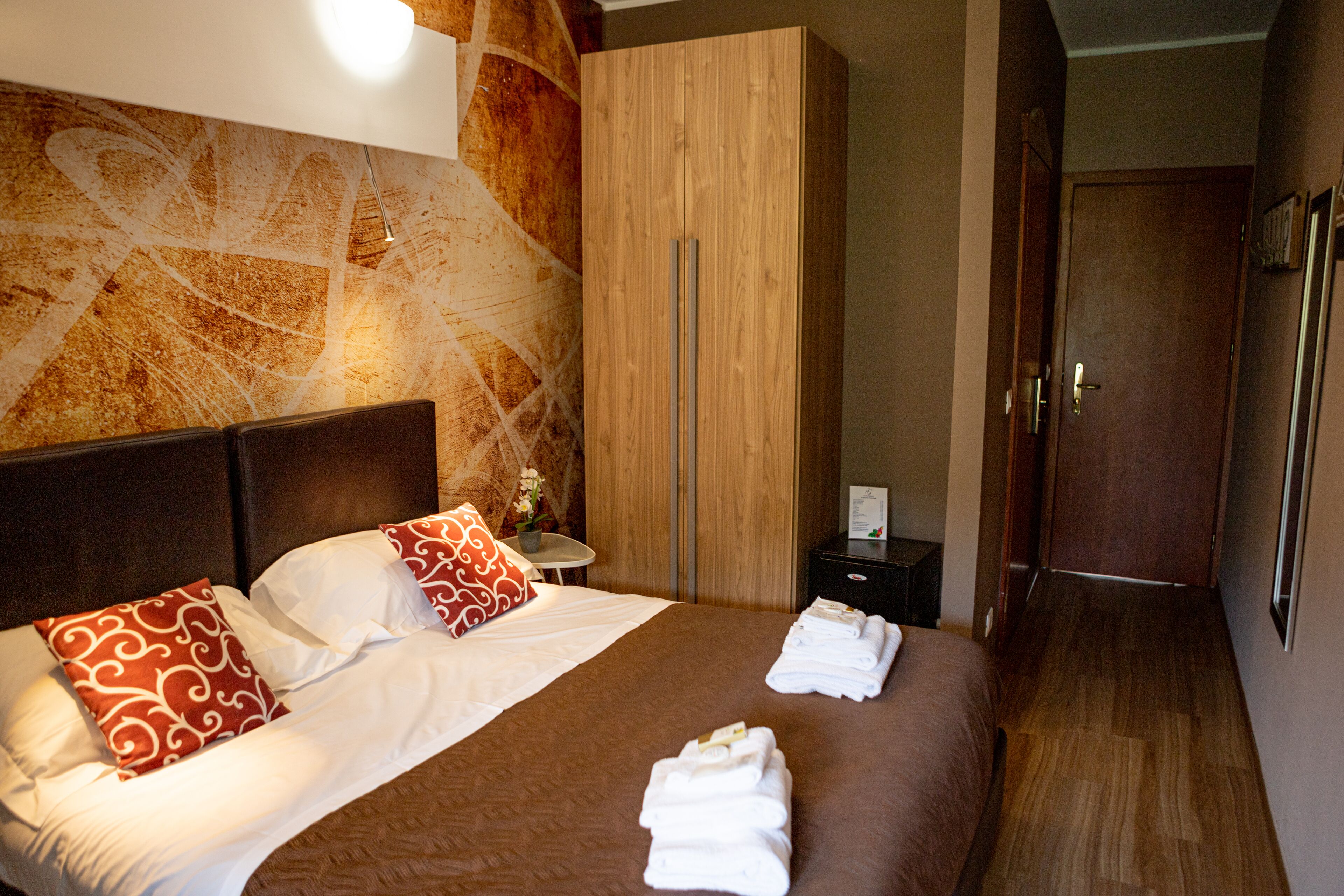 Une chambre d’hôtel avec un grand lit, une armoire en bois et un plancher en bois.