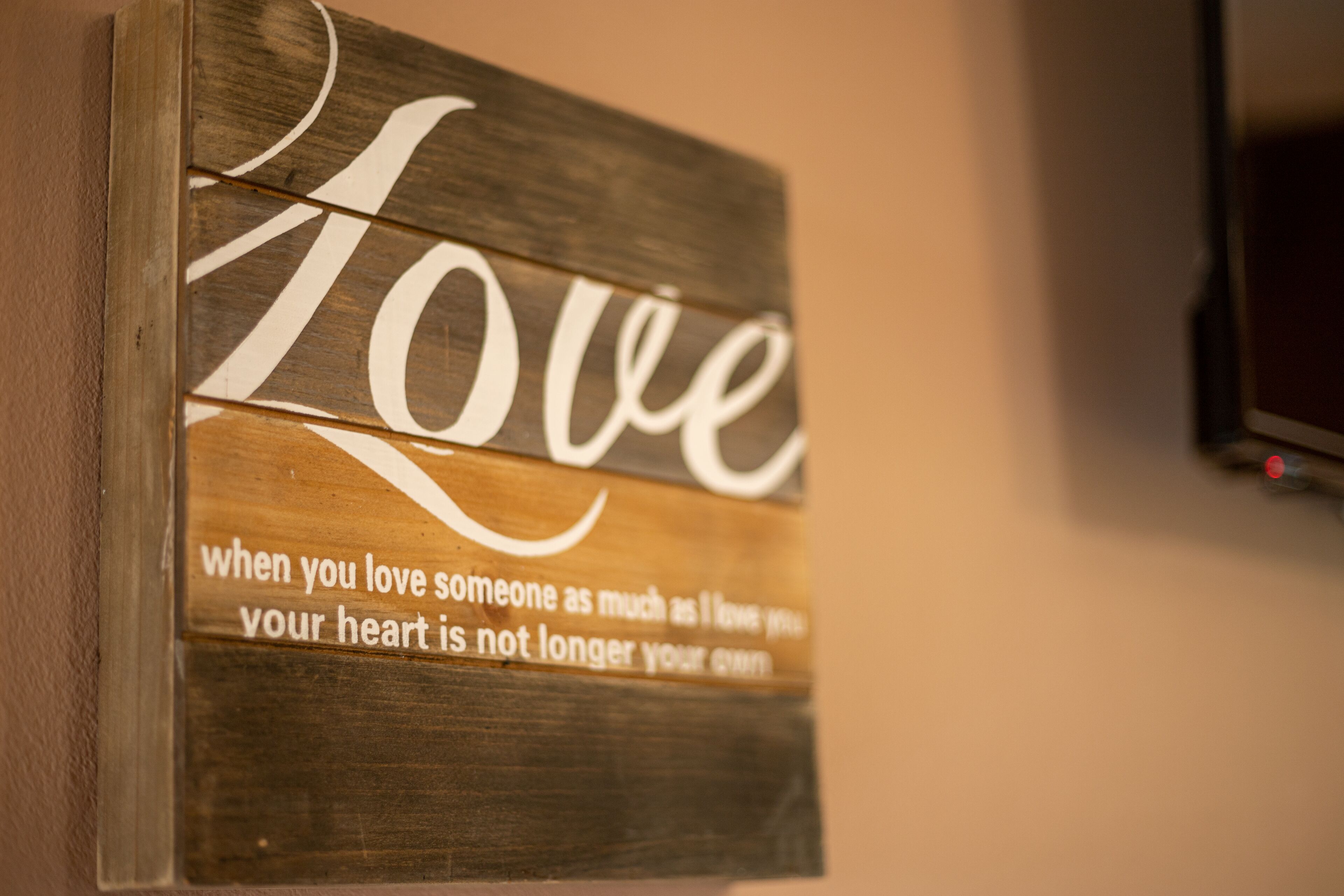Un letrero de madera con la palabra 'Love' y una cita sobre el amor.