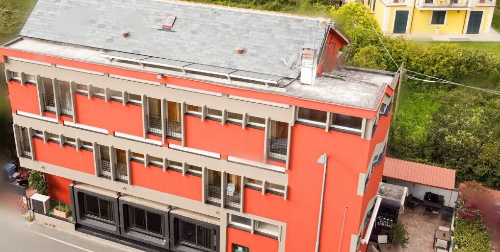 A multi-story building with a flat roof and a red facade.