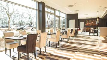 A spacious indoor area with large windows, checkered flooring, and multiple seating arrangements.
