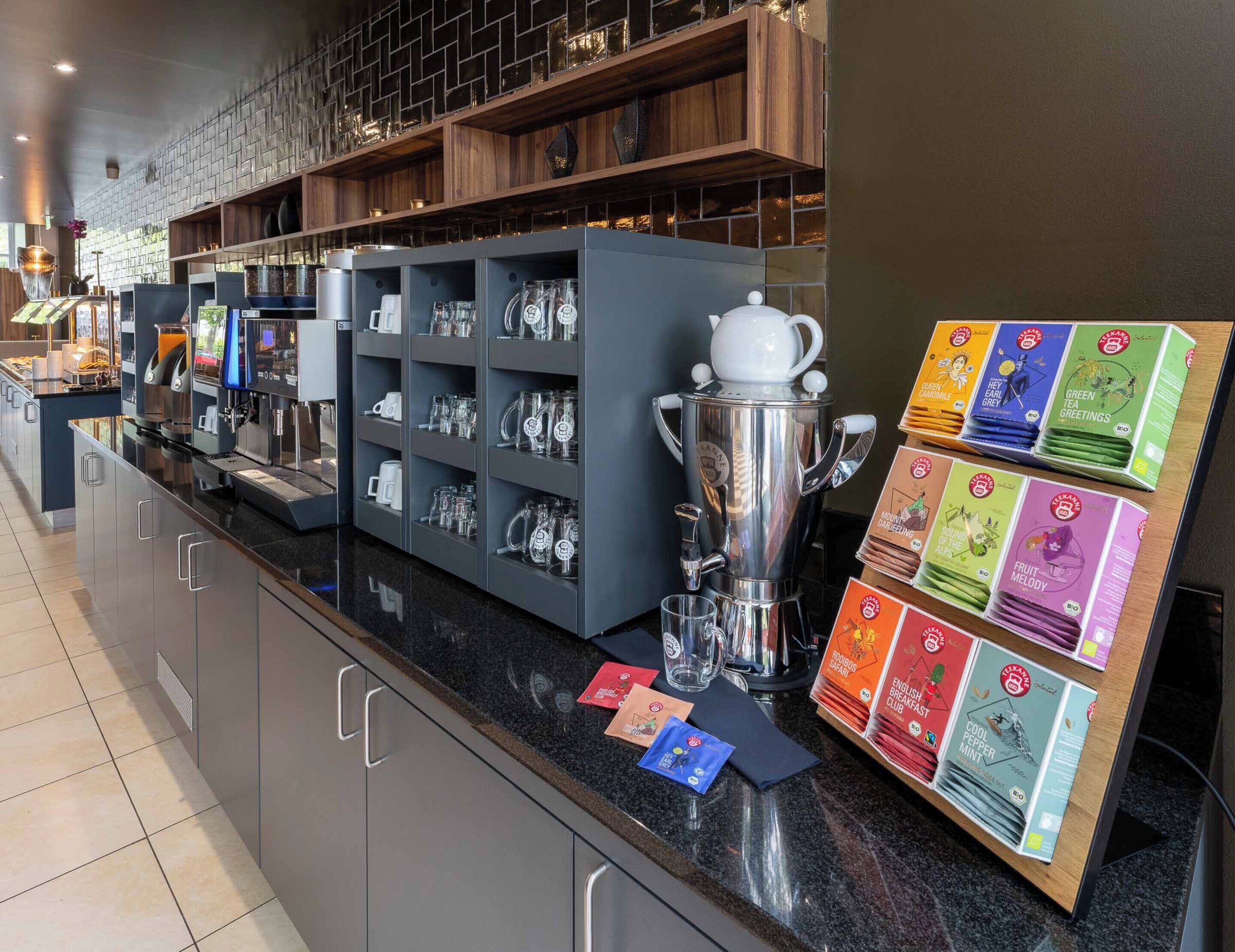 A coffee station with a coffee machine, mugs, and tea packets.