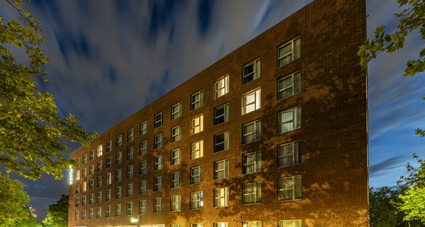Un edificio de varios pisos de ladrillo, con ventanas regularmente distribuidas y techo plano.