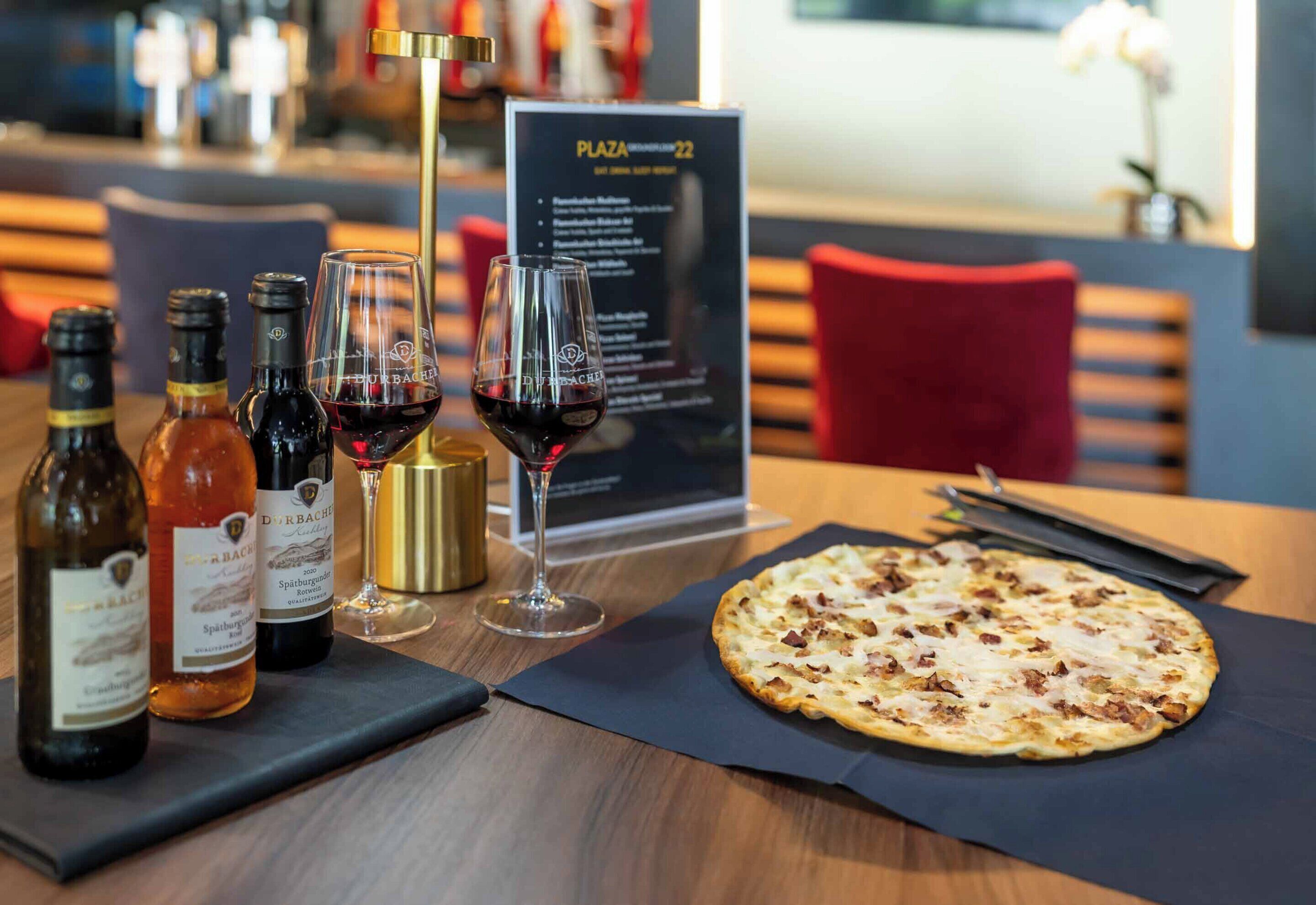 Ett bord med vinflaskor, glas och en pizza.