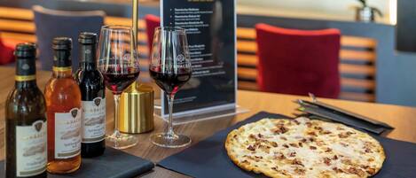 Una mesa con botellas de vino, copas y una pizza.