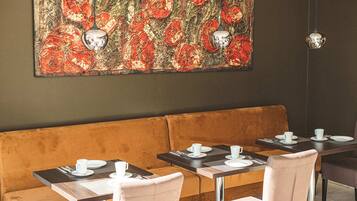 A restaurant with a brown cushioned bench seating, a table with a placemat, and a large floral artwork on the wall.