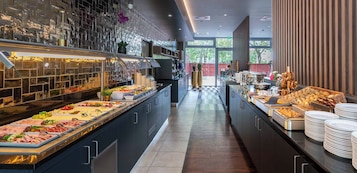 Zona de buffet con diversas opciones de comida, piso a cuadros y vista al exterior a través de amplias ventanas.