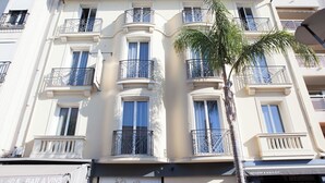A multi-story building with balconies, a palm tree, and a restaurant sign. - Hotel La Villa d'Elsa (Antibes)