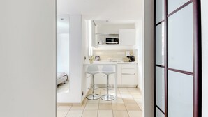 A modern kitchen with white cabinets, a microwave, and two bar stools. - Hotel La Villa d'Elsa (Antibes)