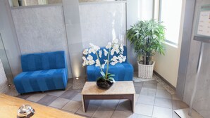 A reception area with a blue sofa, a small table with a potted orchid, and a bamboo plant. - Hotel La Villa d'Elsa (Antibes)