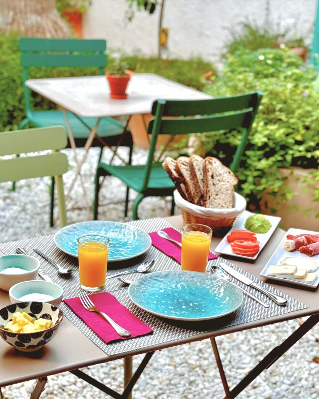 A table set for breakfast with plates, bowls, and glasses of orange juice.