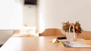 Una mesa con una planta en maceta, un control remoto y algunos papeles.