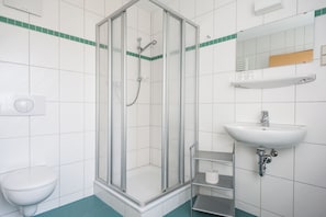 A bathroom with a glass-enclosed shower, a white sink, and a toilet.
