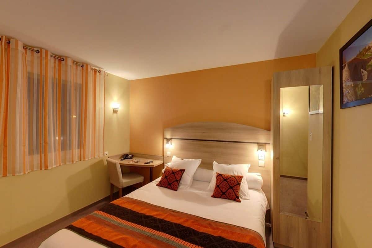 Una habitación de hotel con cama, mesita de noche, silla y escritorio.