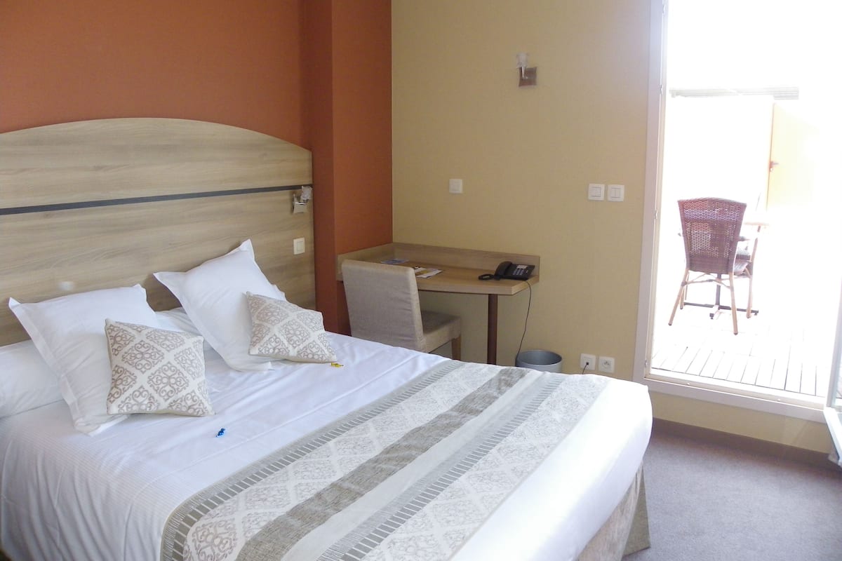 Una habitación de hotel con una cama, un escritorio y una silla.