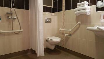 A bathroom with a toilet, shower, and grab bars.