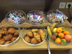 Un buffet de petit-déjeuner proposant une variété d’aliments, notamment des viennoiseries, des fruits et des en-cas emballés.
