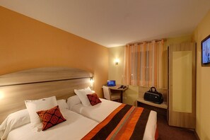 Une chambre d’hôtel avec un grand lit, un bureau avec un ordinateur portable, une télévision et une valise.