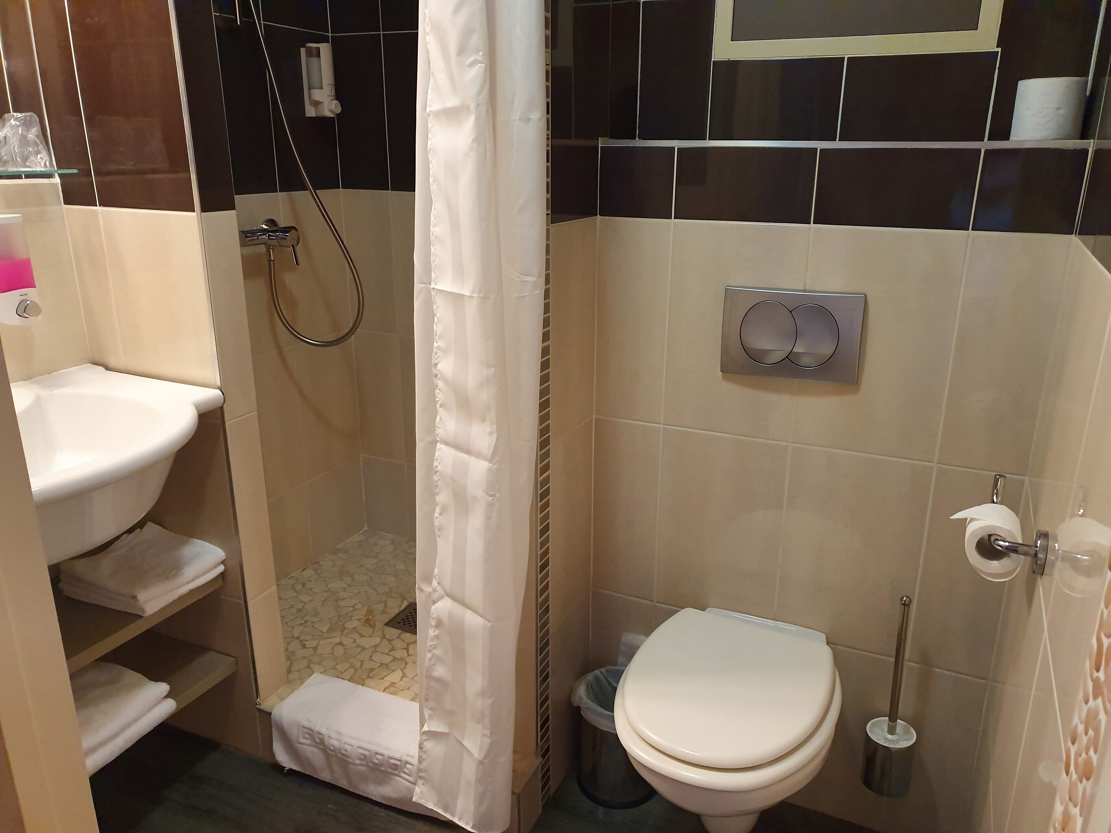 A bathroom with a shower, toilet, and sink.