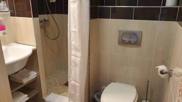 A bathroom with a shower, toilet, and sink.