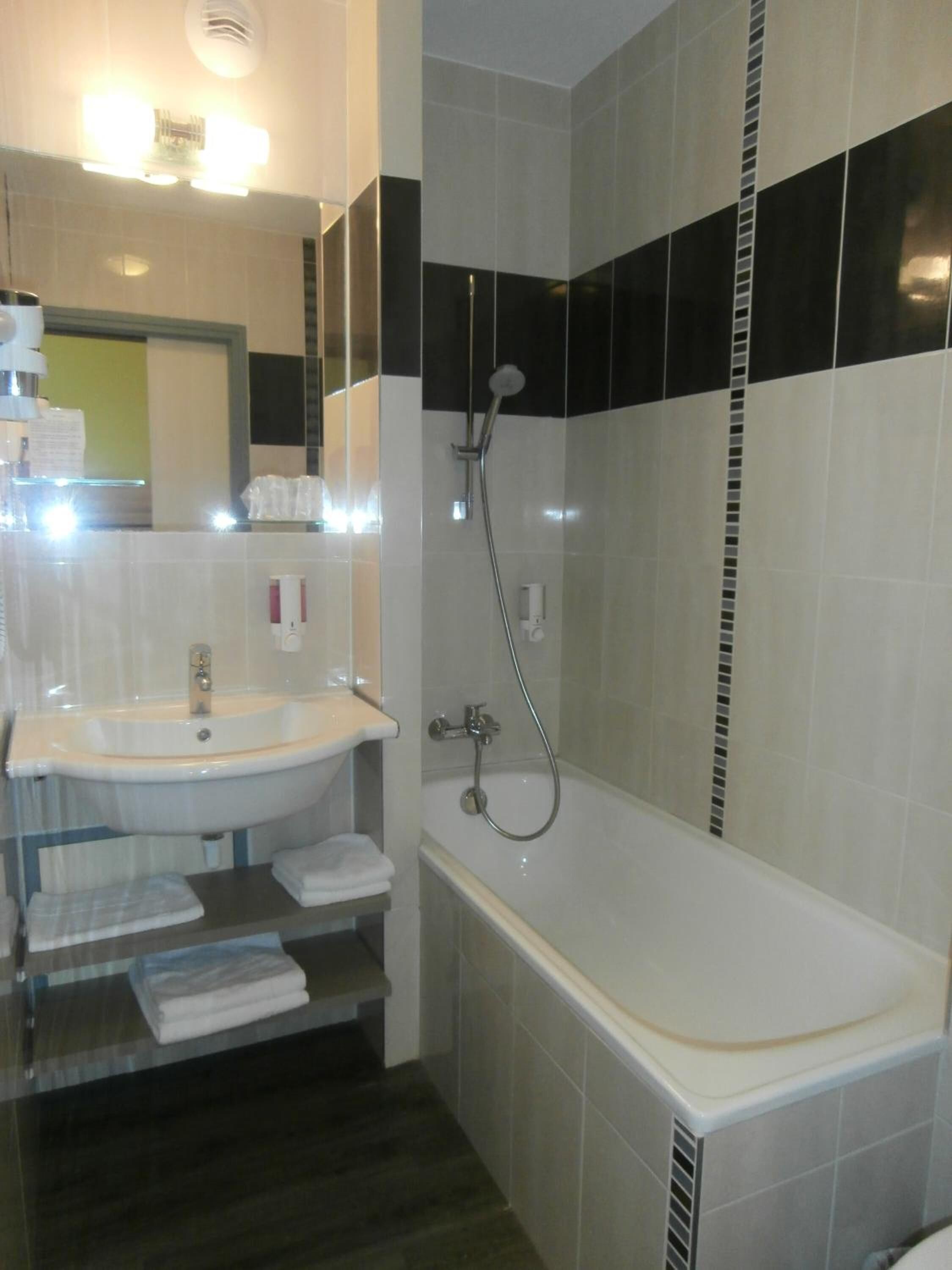 A modern bathroom with a white sink, a bathtub, and a shower.