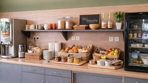 Een ontbijtbuffet met diverse etenswaren, een koffieapparaat en een koelkast.