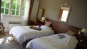Habitación de hotel con dos camas, un escritorio, una silla, un espejo y una ventana con cortinas.