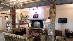 Una sala de estar acogedora con muebles estampados, una chimenea y un televisor montado en la pared.