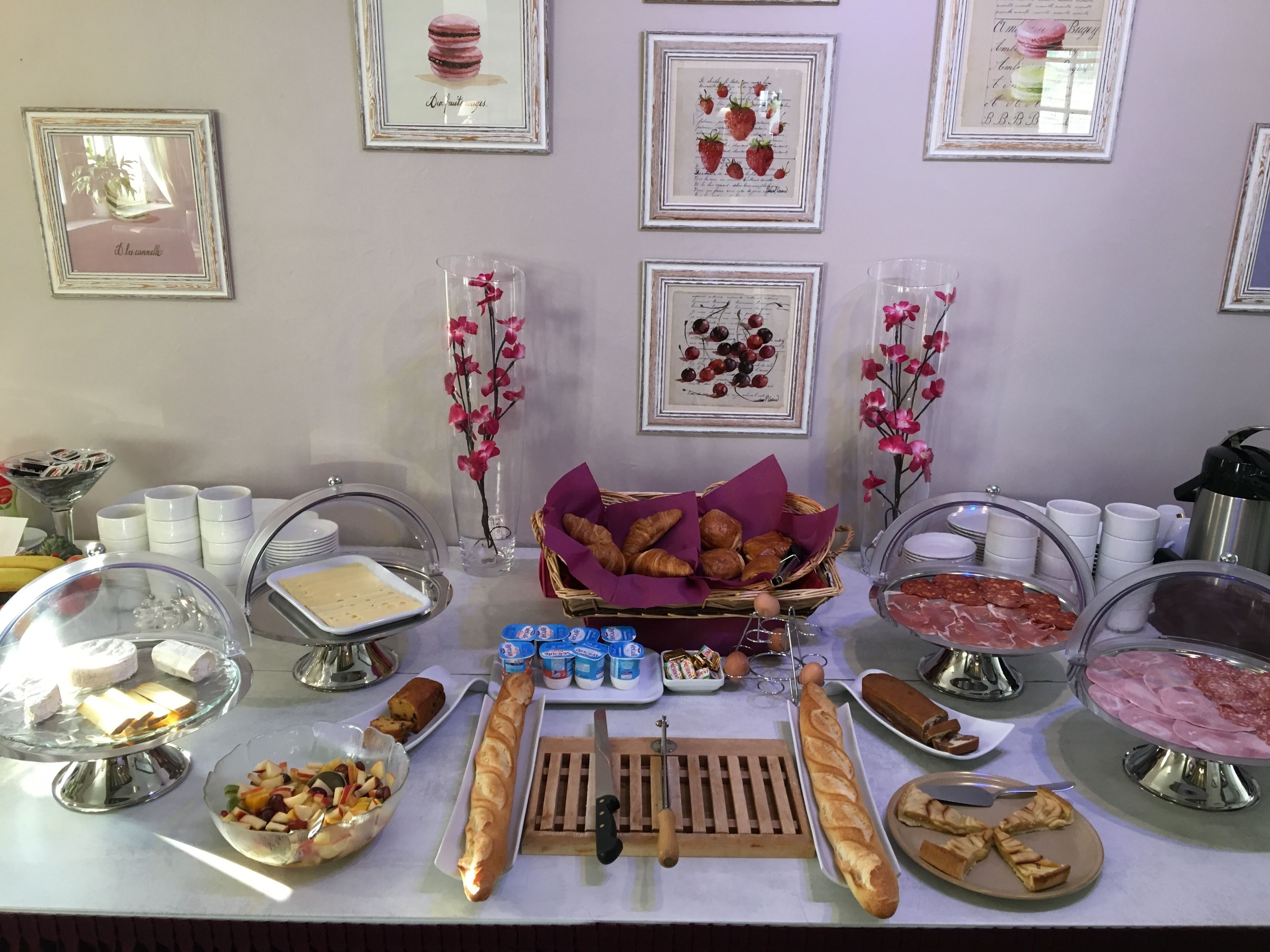 Una mesa de buffet con diversos alimentos, entre ellos pasteles, carnes y postres, dispuesta sobre un mantel blanco.