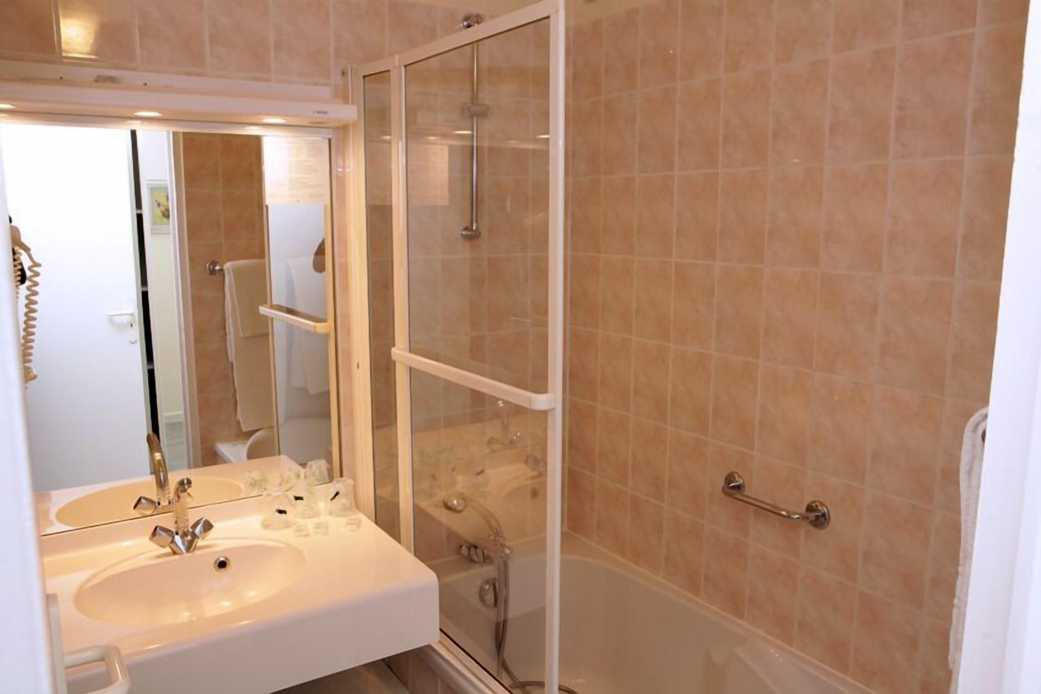 A bathroom with a sink, mirror, and glass-enclosed shower.