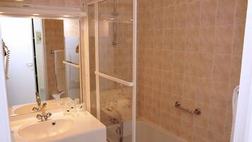 A bathroom with a sink, mirror, and glass-enclosed shower.