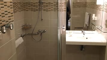 A bathroom with a glass-enclosed shower, a sink, and a toilet.