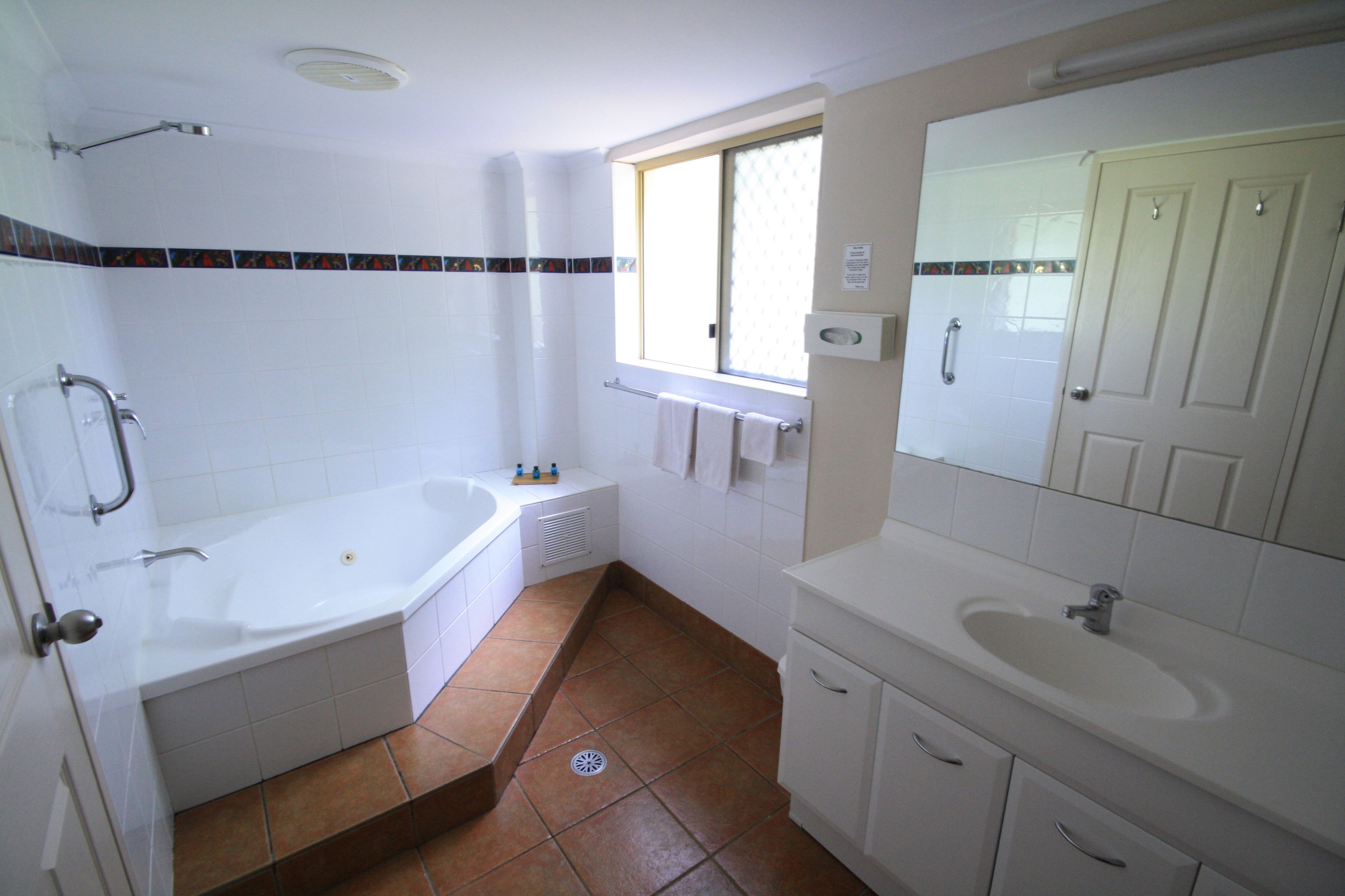 A bathroom with a bathtub, a sink, and a window.