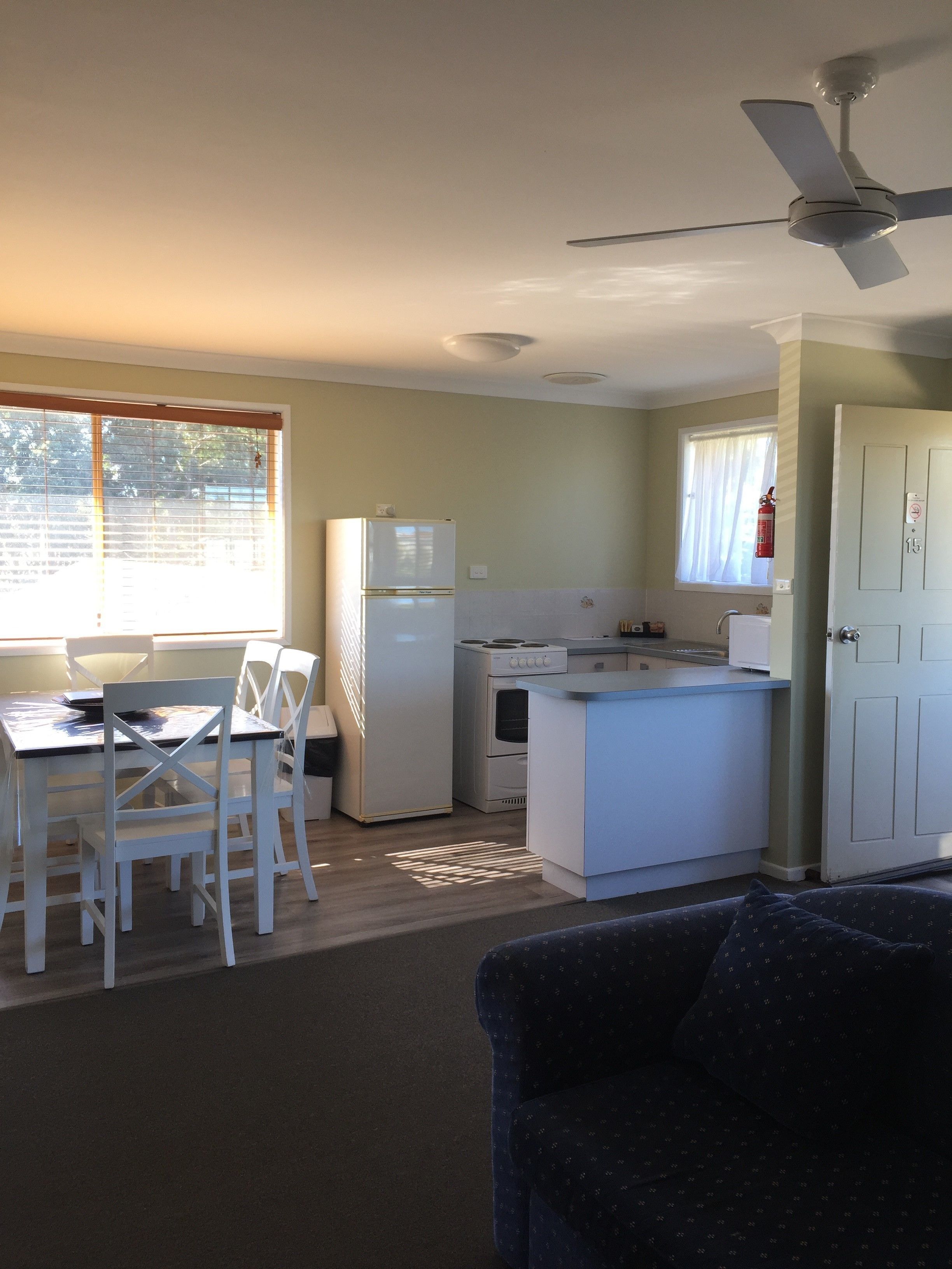 A compact kitchen with a refrigerator, stove, and dining area with chairs.