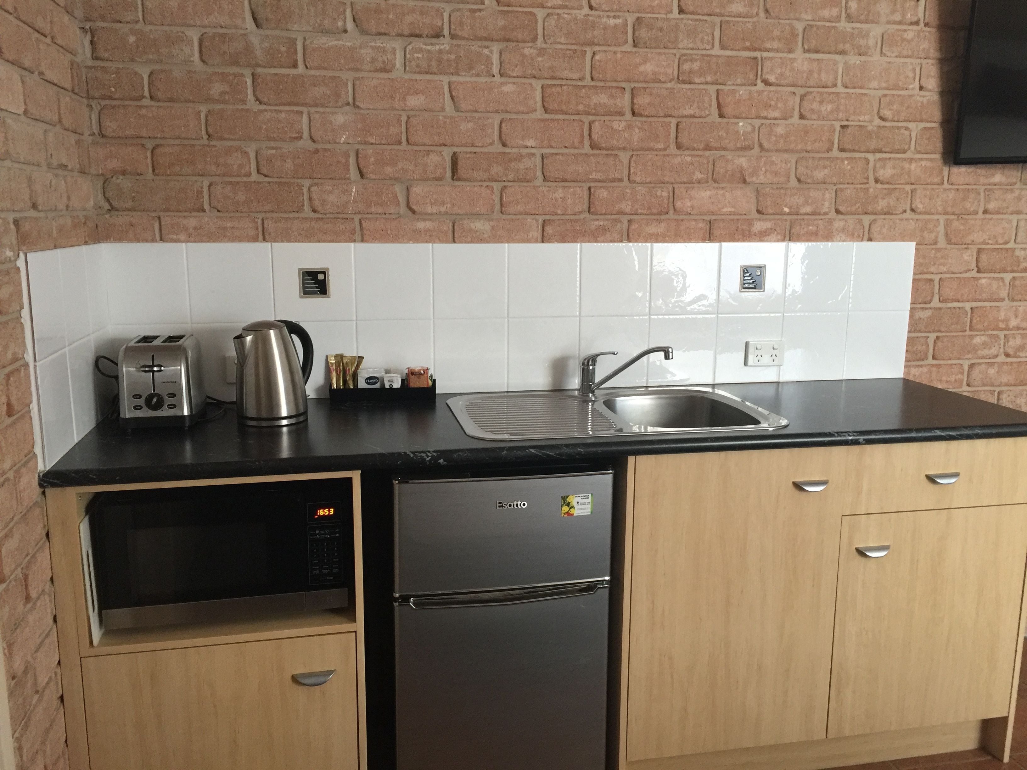 Kompakti keittiö, jossa on työtasolla leivänpaahdin, vedenkeitin ja espressokone, sekä pesuallas ja astianpesukone.