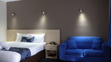 Ein Hotelzimmer mit einem Bett, einem blauen Sofa und zwei Wandleuchten.