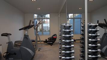 A gym with exercise equipment, including treadmills and dumbbells, and large windows providing natural light.