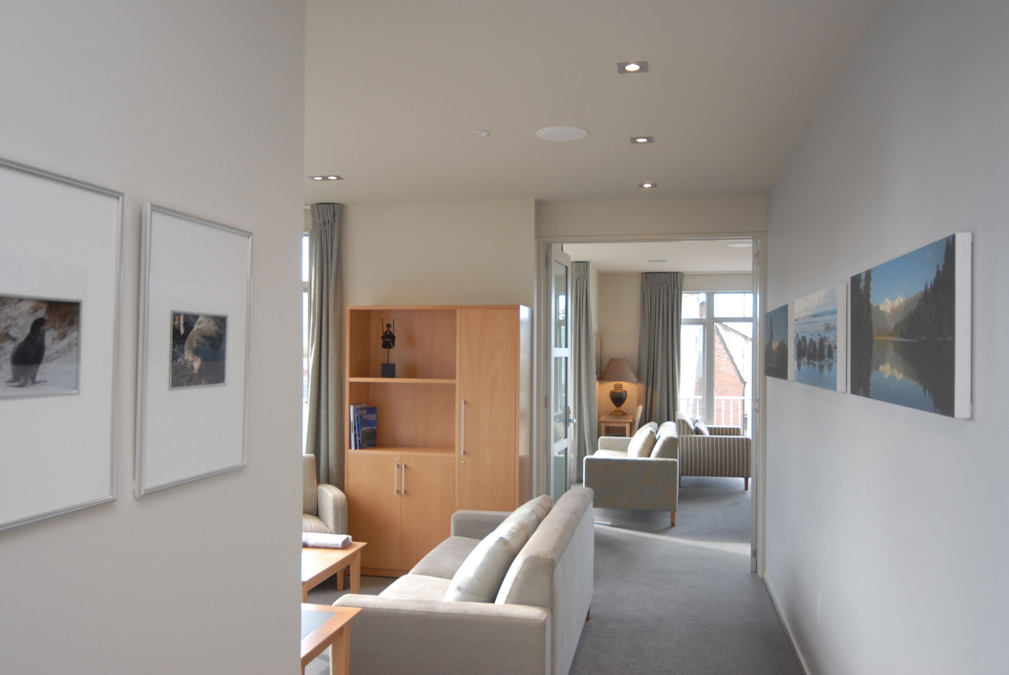 Habitación de hotel moderna con sofá, un armario de madera y vistas al exterior.